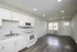 Bright, modern kitchen and living area with sleek cabinetry, stainless appliances, and rich hardwood flooring.