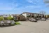 Charming multi-unit apartment complex with brick facade, ample parking, and lush greenery under a clear blue sky at Zen Long Island.