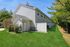 Charming townhouse exterior featuring lush green lawn and white privacy fencing under a clear blue sky.