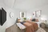 Elegant bedroom with modern decor, featuring a cozy bed with orange bedding, stylish artwork, and a large wall-mounted TV.