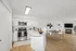Bright and modern open-concept kitchen and dining area with sleek appliances and stylish wooden flooring, featuring a cozy fireplace and elegant decor.