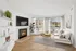 Bright, contemporary living room with a cozy fireplace, chic furnishings, and large windows offering a charming view.