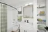 Elegant bathroom with modern fixtures, featuring white cabinetry, stylish mirror, and organized shelving adorned with colorful towels.