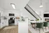 Modern open-concept kitchen and dining area with sleek white cabinets, stainless steel appliances, and elegant green dining chairs under a stylish pendant light. Inviting atmosphere with a cozy fireplace and contemporary design.