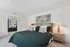 Elegant bedroom featuring a luxurious king-size bed with chic pillows, stylish artwork, mirrored closet doors, and a modern bedside lamp for a cozy and sophisticated ambiance.