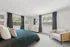 Bright and cozy bedroom with a large bed, elegant decor, and natural light streaming through two windows.