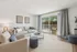 Bright and airy living room with elegant decor, featuring a cozy gray sofa, stylish armchair, and expansive sliding glass doors leading to a scenic balcony.