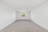 Bright and airy room with plush carpeting and a large window showcasing serene greenery views.