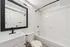 Modern bathroom featuring a sleek white vanity with black fixtures, large elegant mirror, and a pristine bathtub accentuated by white tiles.