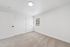 Bright and spacious bedroom featuring plush carpet flooring, modern light fixture, and abundant natural light from a large window.