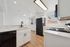 Modern kitchen with sleek marble countertops, black appliances, and ample natural light.