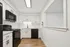 Contemporary kitchen with sleek black appliances, pristine white cabinetry, and elegant wood flooring.