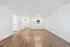 Elegant open-concept living space showcasing sleek hardwood floors, bright neutral walls, and a convenient kitchen pass-through.