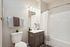 Contemporary bathroom featuring a sleek white sink, stylish dark vanity, and modern striped shower curtain. Cozy accents include soft towels and a small potted plant, creating a fresh and inviting atmosphere.