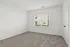 Inviting sunlit room with plush carpet and large window, perfect for a cozy bedroom or serene home office.