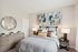 Inviting bedroom with modern decor, featuring abstract art, cozy bedding, and elegant lighting for a serene ambiance.