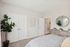 Bright and inviting bedroom with modern decor, featuring a plush bed, elegant mirror, stylish dresser, and vibrant indoor plants.