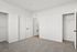 Pristine white bedroom with plush carpet, two spacious closets, and open doors inviting natural light.