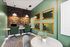 Chic co-working space with elegant green chairs, dual computer stations, and decorative mirrors, perfect for productivity.