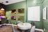 Chic office nook with elegant green walls, modern desk setup, and cozy round table for collaborative work.