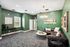 Modern living room with chic green walls, stylish lighting fixture, and sophisticated decor creating a warm, inviting atmosphere.