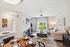 Inviting open-concept living room featuring cozy fireplace, modern dining area, and bright glass doors leading to a lush garden view.