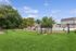 Charming community dog park with lush greenery, fenced play area, and picnic spot, perfect for pet-friendly living.