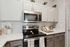 Modern kitchen showcasing sleek stainless steel appliances, pristine white cabinetry, and elegant subway tile backsplash.