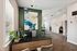 Modern office interior with stylish decor, featuring a vibrant abstract painting on a green accent wall, sleek desk, and lush plants, creating a welcoming workspace.