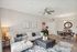 Contemporary open-plan living and dining area with elegant decor, featuring a plush sofa, modern coffee table, and a stylish dining set, accented with chic artwork and a ceiling fan.