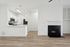 Contemporary kitchen with sleek white cabinetry, stainless steel appliances, and spacious countertops, adjacent to a cozy living area with a modern fireplace.
