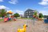 Inviting apartment complex with modern architecture, featuring a vibrant playground set against a clear blue sky, perfect for family living.