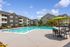 Inviting apartment enclave with a pristine swimming pool, sun loungers, and elegant outdoor seating, perfect for relaxation and leisure.