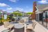 Charming outdoor patio area with contemporary wicker seating, vibrant green umbrellas, and a sparkling pool, ideal for relaxation and social gatherings.