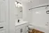 Sleek bathroom with modern fixtures, featuring a pristine white vanity, elegant lighting, and a stylish bathtub with wood-style flooring.