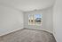 Bright and airy carpeted room with large window overlooking a scenic view, perfect for a cozy bedroom or serene office space.