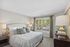 Bright and airy bedroom featuring a plush bed with decorative pillows and large window with serene outdoor view.