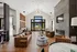 Elegant modern living room with high vaulted ceilings, stylish chandelier, and sleek leather furniture, featuring a grand fireplace and expansive windows with natural light.