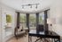 Bright and inviting home office with large windows, stylish desk, and cozy seating area, perfect for work from home comfort.