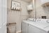 Chic laundry room with modern washing machine and dryer, artistic wall decor, and ample shelf storage.