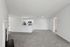Modern open living area with plush carpet, a cozy fireplace, and a sleek kitchen with stainless steel appliances.