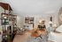 Chic open-concept living room with modern decor, cozy seating, stylish shelving, and a sleek kitchen island with bar stools.