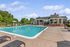 Inviting outdoor pool area with luxurious seating, surrounded by lush greenery and modern clubhouse.