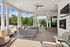 Charming outdoor lounge area featuring cozy seating, elegant fireplace, and modern ceiling fan, ideal for relaxation and entertaining.