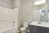 Elegant bathroom with modern fixtures, featuring a sleek vanity, large mirror, and a pristine shower in a stylish apartment.