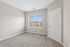 Bright, airy room with plush carpeting and a large window offering lovely residential views, perfect for a serene retreat.