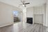 Bright and modern living room with sleek hardwood floors, elegant fireplace, ceiling fan, and sliding glass doors leading to a cozy balcony.