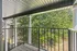 Charming balcony with elegant pillars, offering a tranquil view of lush green trees.