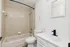 Modern bathroom featuring sleek white cabinetry, a chic black faucet, and a pristine bathtub with stylish wall tiles.