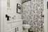 Inviting bathroom with elegant floral shower curtain, stylish white vanity, and modern black fixtures.
